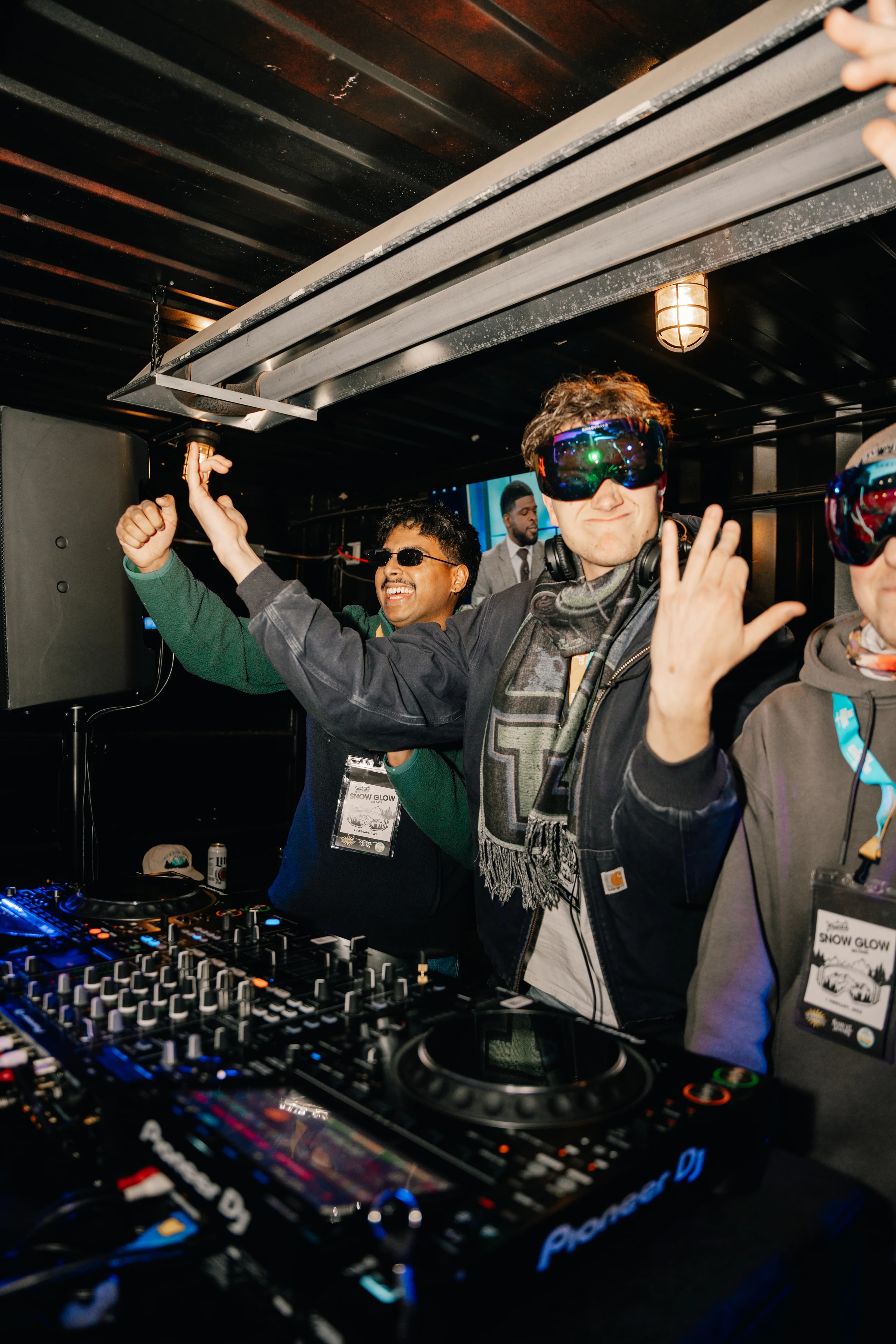 A DJ in ski goggles celebrating at the decks